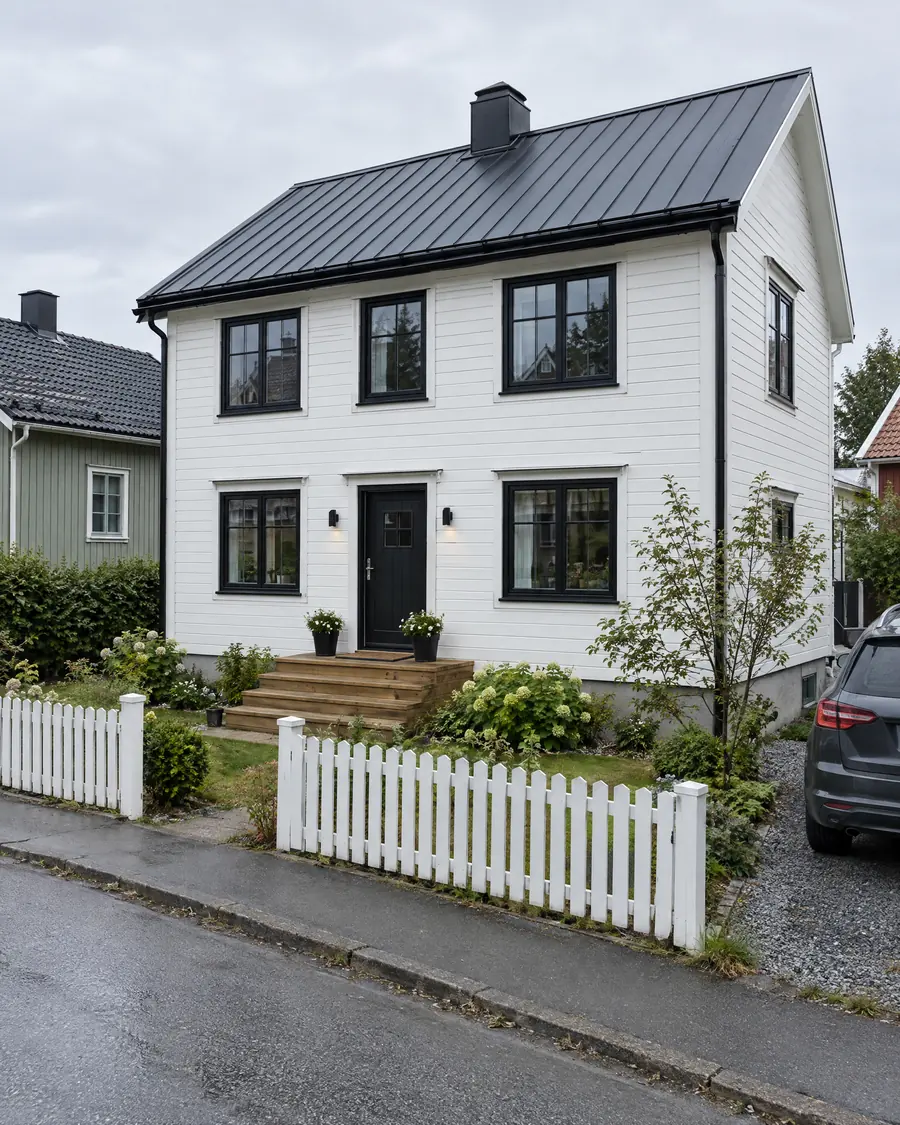 Gamalt timburhús við nýggjum hvítum klædningi, svørtum vindeygum og nýggjum taki
